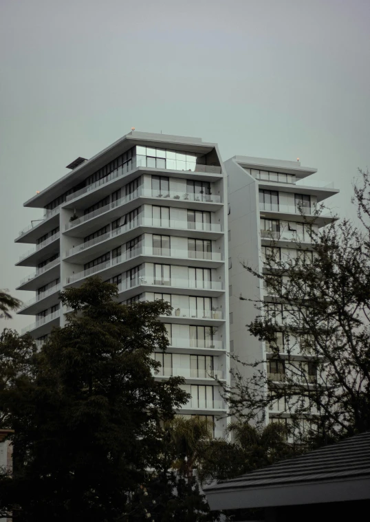 a tall building sitting on top of a lush green hillside, inspired by Ned M. Seidler, brutalism, todd hido, wellington, overcast!!!, fancy apartment