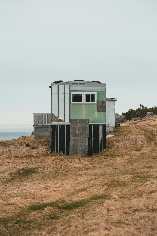 a small building sitting on top of a hill next to the ocean, by Jesper Knudsen, shack close up, museum quality photo, modular, hestiasula head