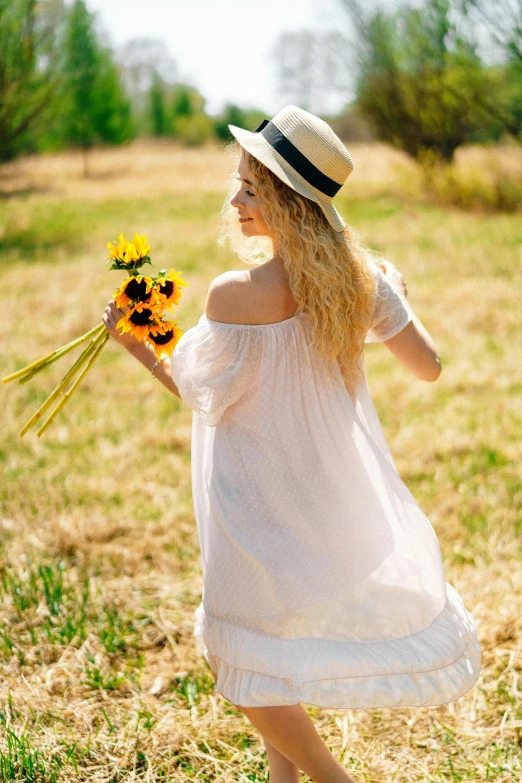 a woman in a white dress holding a bunch of sunflowers, pexels, renaissance, woman with hat, walking away from camera, young blonde woman, delightful surroundings