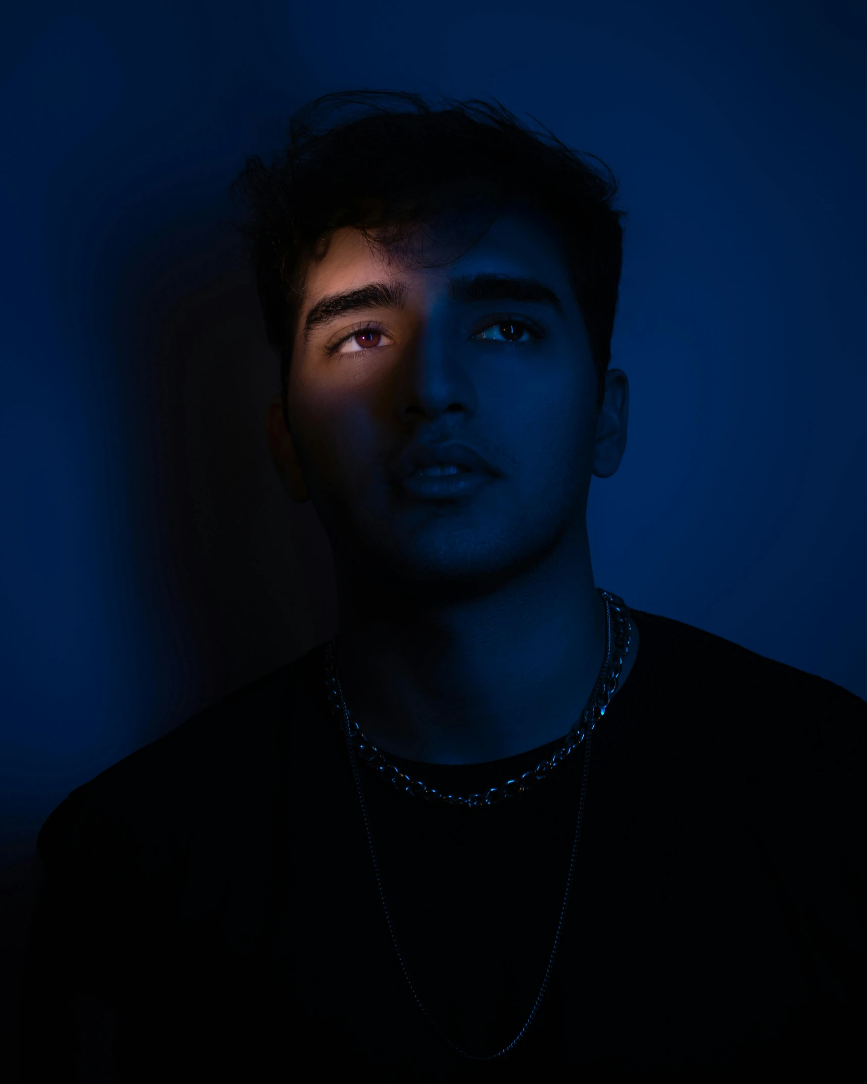 a man with a chain around his neck, an album cover, by Cosmo Alexander, trending on pexels, bisexual lighting, glowing face, ramil sunga, proud looking away