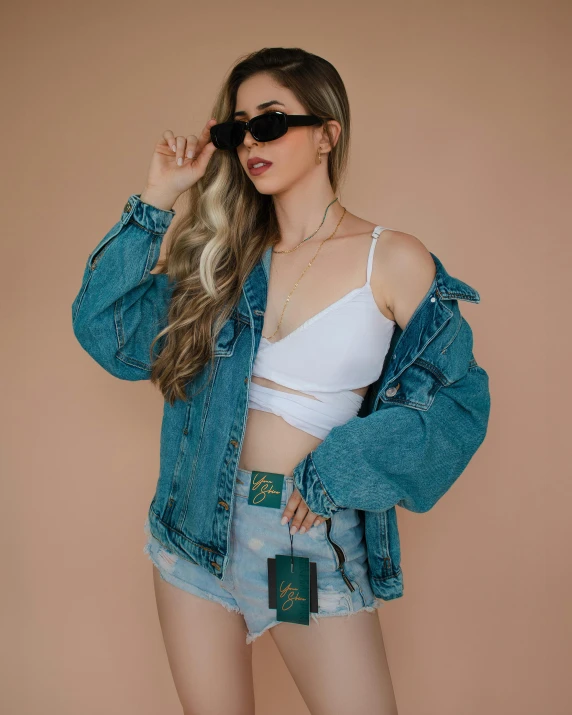 a woman wearing a denim jacket and shorts, trending on unsplash, posing in bra, ((greenish blue tones))