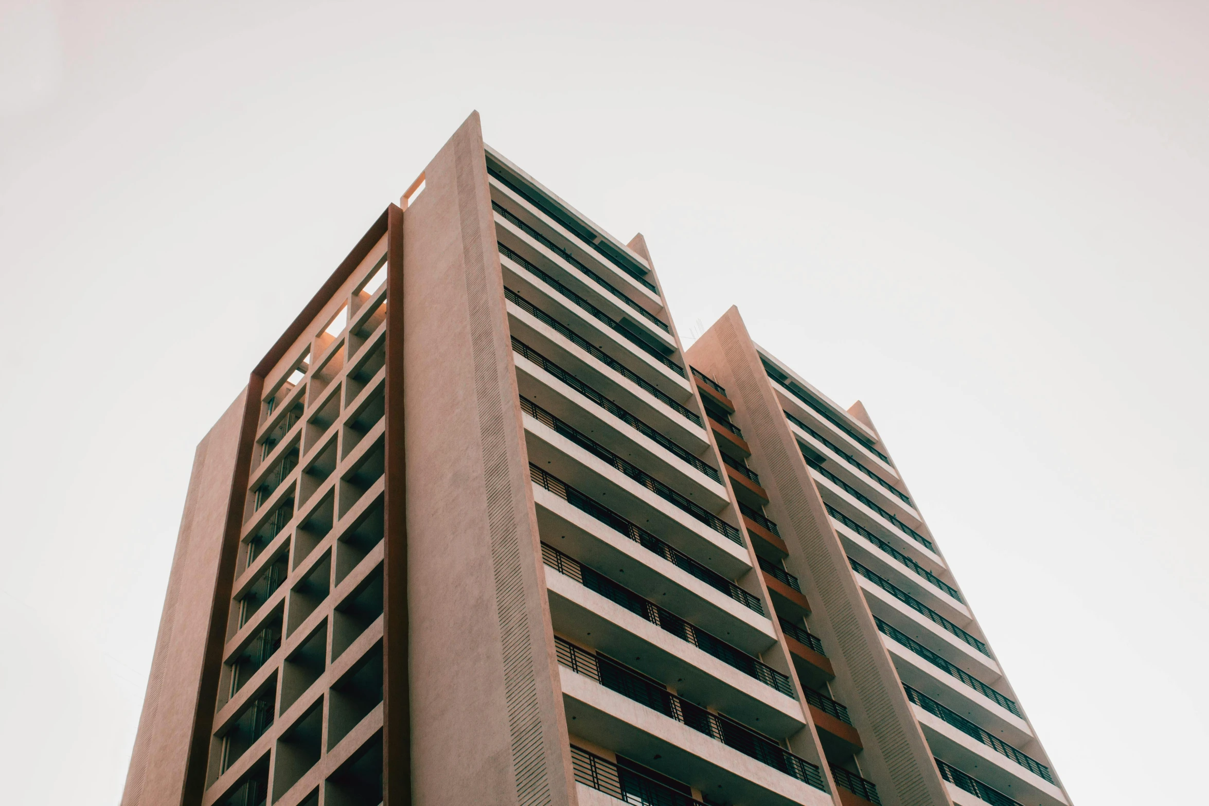 a tall building with a clock on top of it, by Lee Loughridge, unsplash, brutalism, brown, ten flats, 2 0 0 0's photo, up-angle view