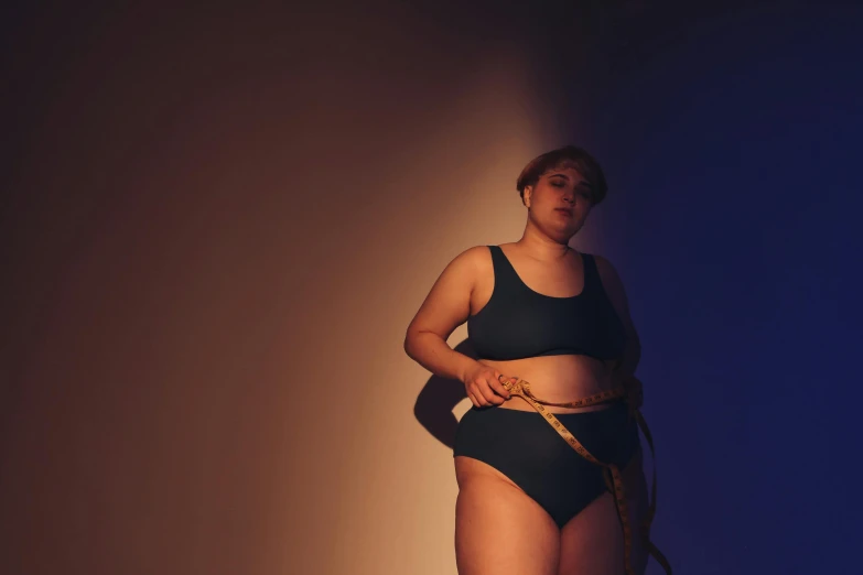 a woman with a measuring tape around her waist, by Emma Andijewska, in the spotlight, plus-sized, blue undergarments, deep colour