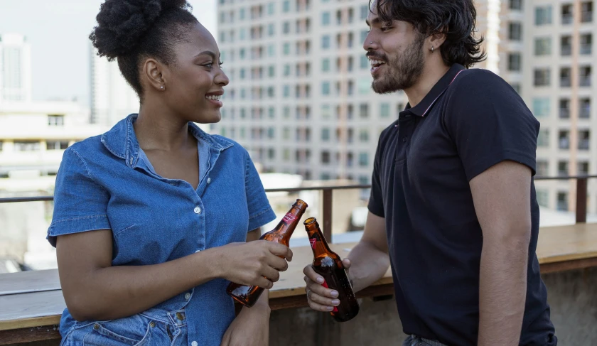 a man and a woman standing next to each other, pexels contest winner, happening, beer bottle, rooftop party, profile image, coka-cola advertisement