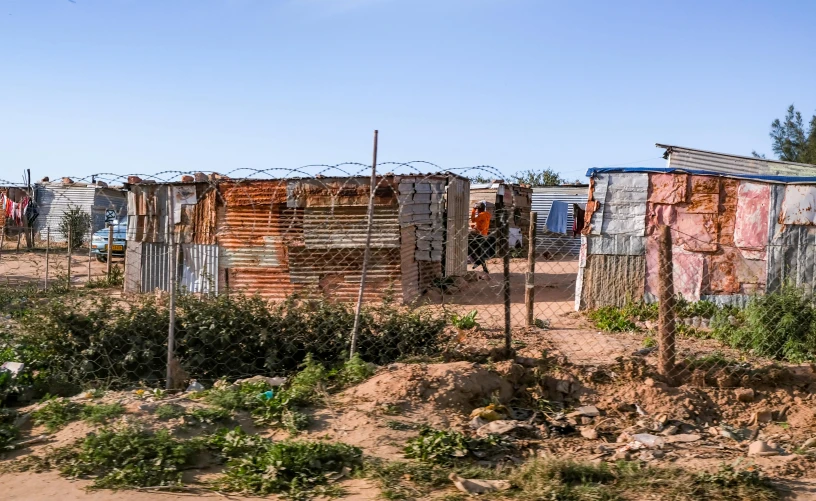 a group of shacks sitting on top of a dirt field, unsplash, standing in township street, samma van klaarbergen, exterior photo, realistic »