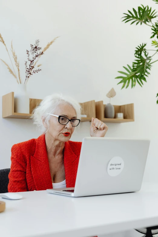 a woman sitting in front of a laptop computer, by Andries Stock, pexels contest winner, white-haired, sitting on a red button, annoyed, next to a plant