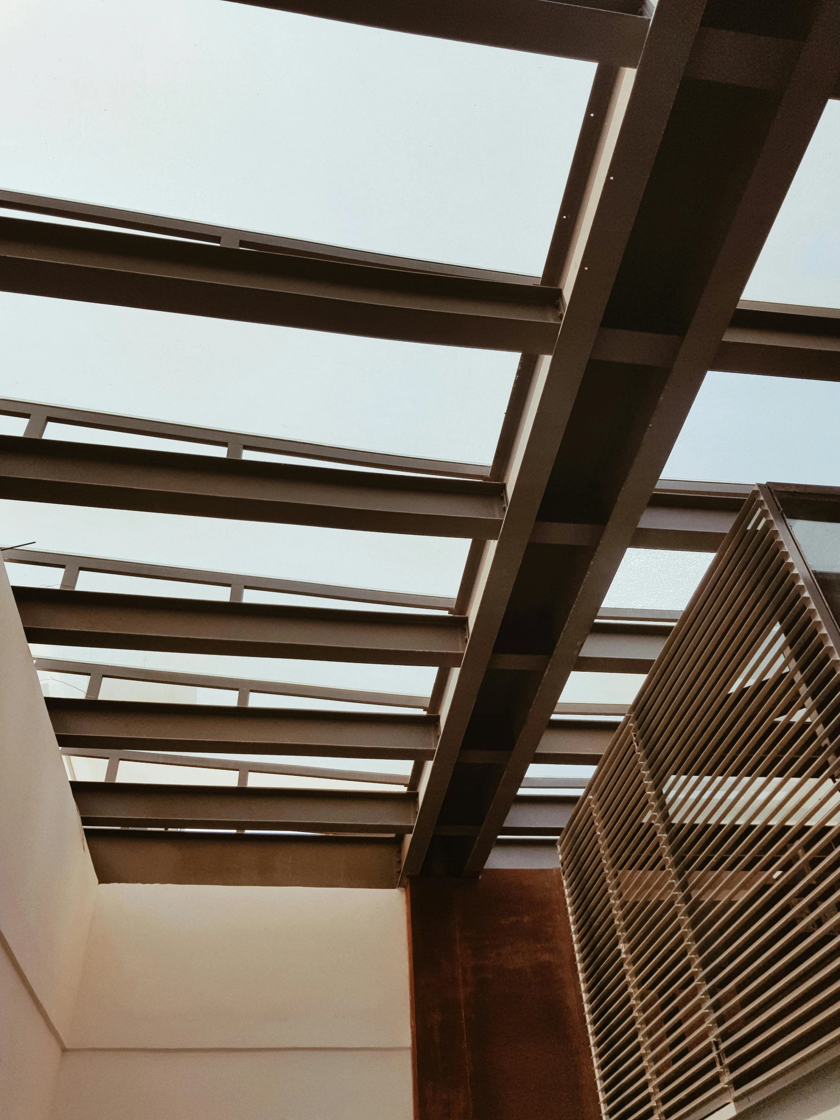 a white toilet sitting under a window next to a radiator, an album cover, unsplash, light and space, sky made of ceiling panels, canopies, steel archways, transparent corrugated glass