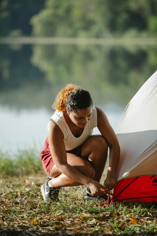 a woman setting up a tent next to a lake, friendly face, sturdy body, ariel perez, fan favorite