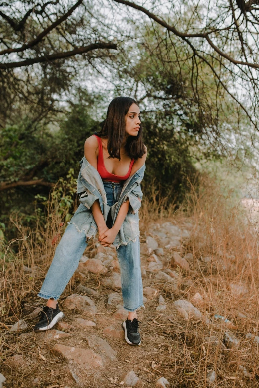 a woman sitting on a rock in a field, trending on pexels, baggy jeans, young middle eastern woman, profile image, standing