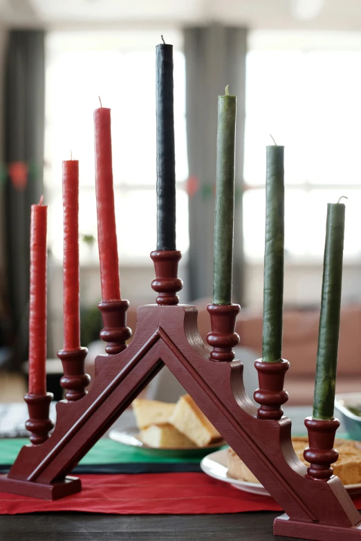 a group of candles sitting on top of a table, inspired by Ernest William Christmas, folk art, gothic arch frame, red and green tones, morning detail, medium-shot