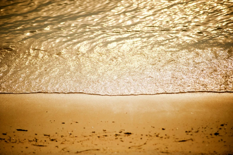 a surfboard sitting on top of a sandy beach, gold refractions off water, golden hour photograph, dappled sunlight, sand banks