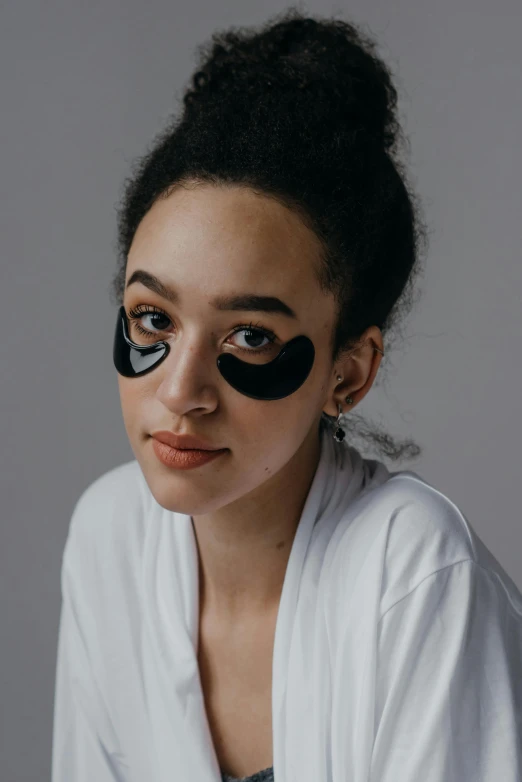 a woman with black eye patches on her face, by Julia Pishtar, trending on pexels, photoshoot for skincare brand, wavy, jet - black skin, lazy eyes