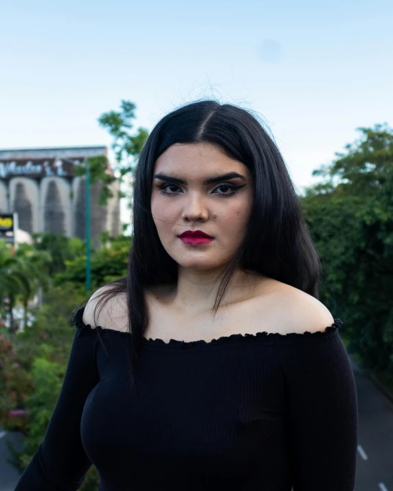 a woman in a black top posing for a picture, by reyna rochin, dark eyebrows, trans rights, temples behind her, mariel hemmingway
