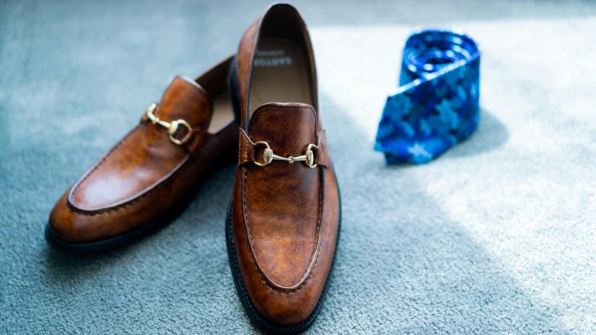 a pair of shoes sitting on top of a carpet, inspired by Gaetano Sabatini, pexels contest winner, wearing robes and neckties, brown, slides, realistic detail