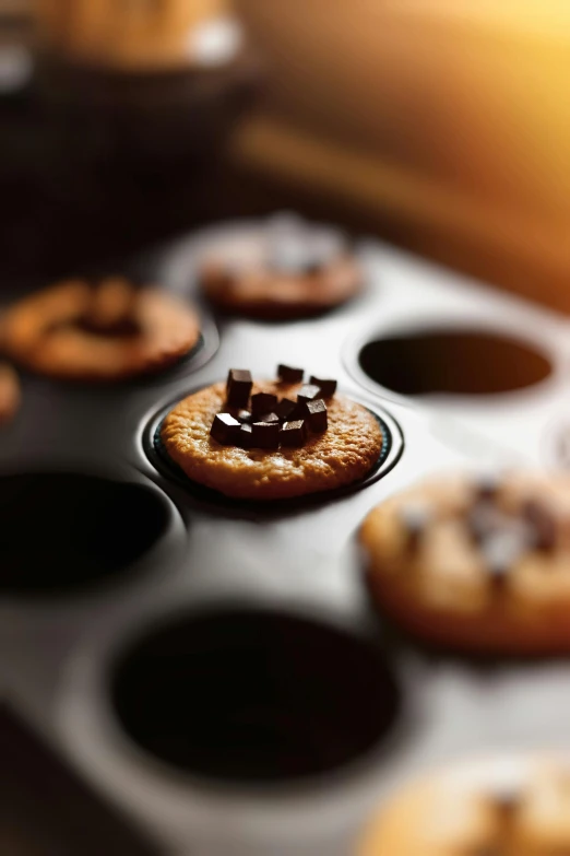 a close up of a muffin pan filled with cupcakes, a still life, by Andries Stock, trending on pexels, baking cookies, molten, short dof, gears