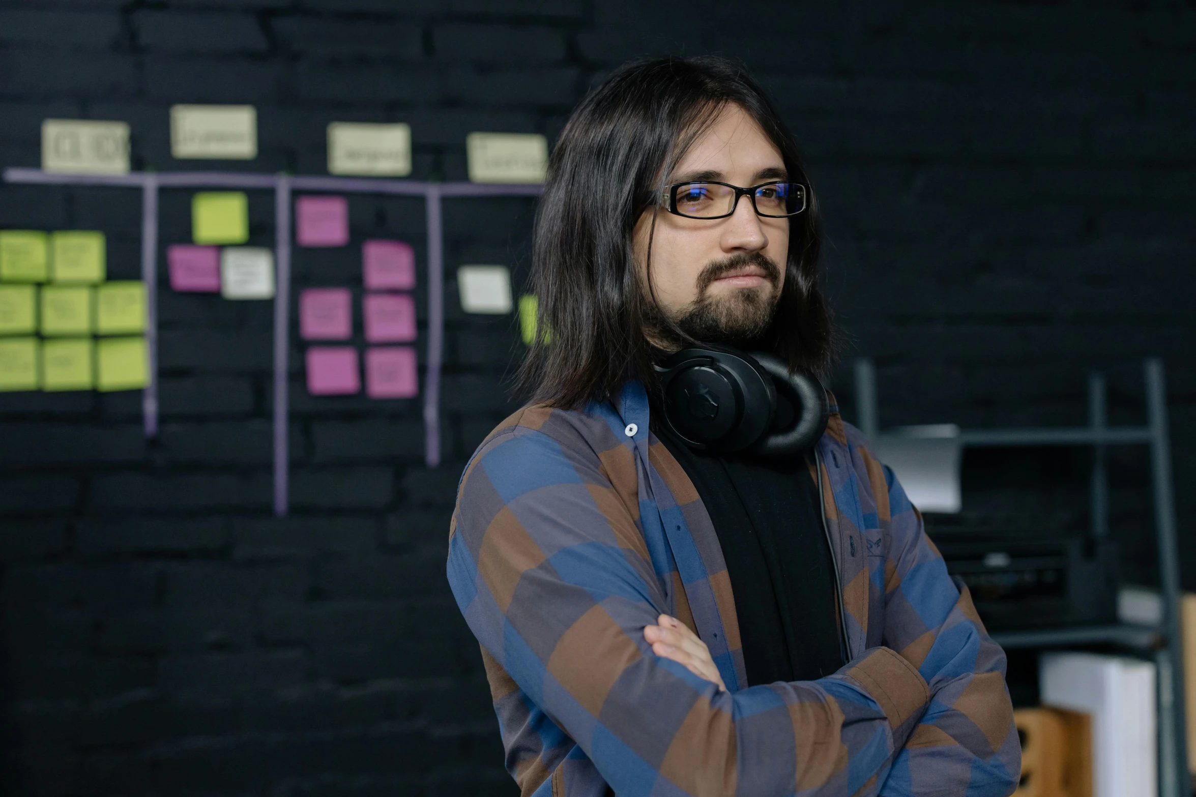 a man standing in front of a wall with post it notes on it, wearing gaming headset, young with long hair, substance designer, avatar image