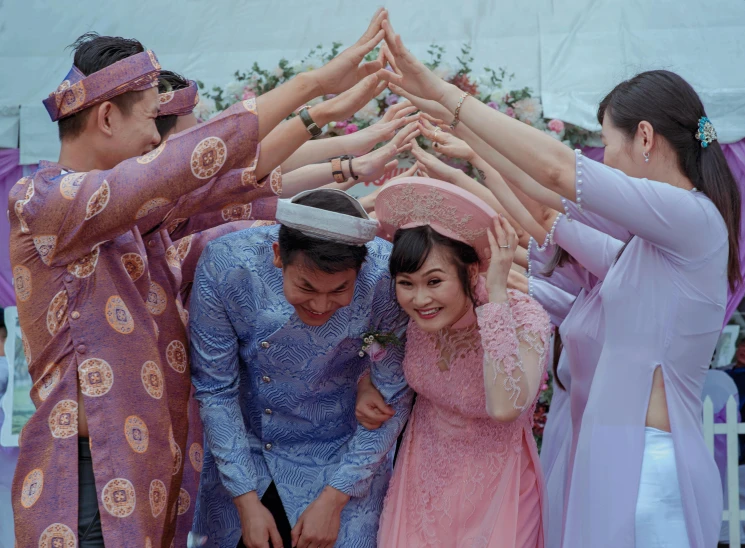 a group of people standing around each other, by Alice Mason, pexels contest winner, happening, ao dai, wearing a pink head band, many hands, groom