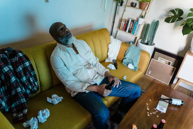 a man sitting on a couch in a living room, pexels contest winner, lance reddick, devastated, playing games, sickness