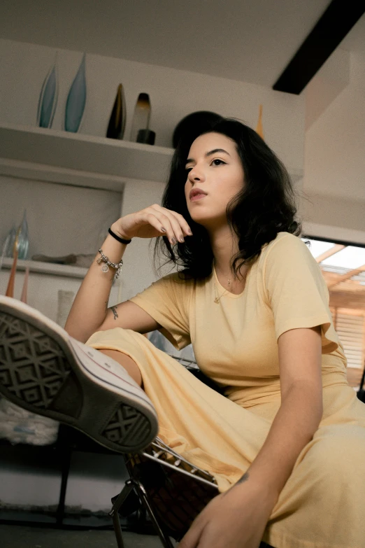 a woman in a yellow dress sitting on a chair, a colorized photo, inspired by Elsa Bleda, pexels contest winner, with black hair, she is wearing streetwear, on a coffee table, promotional image