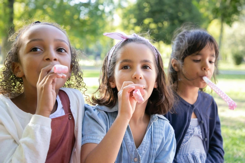 a group of young girls sitting on top of a lush green field, a picture, shutterstock, blowing bubblegum, eating ice cream, 15081959 21121991 01012000 4k, at a park