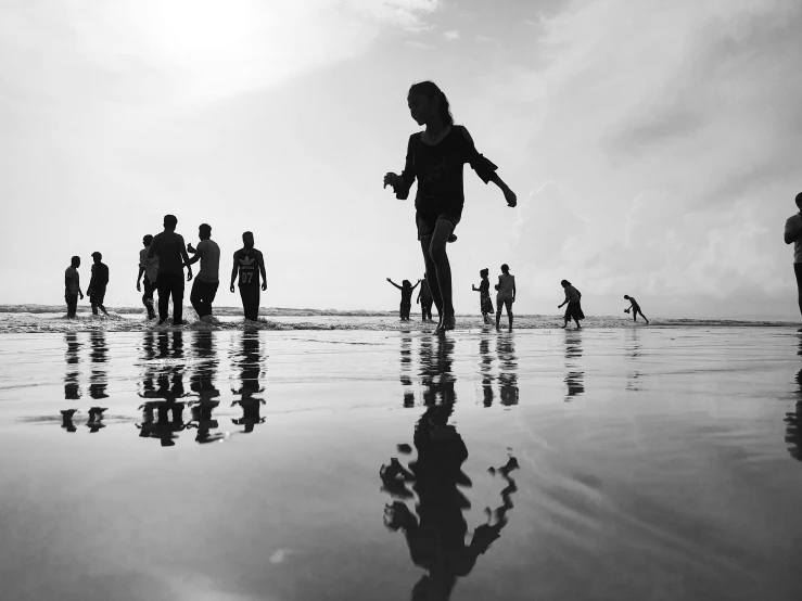 a group of people standing on top of a beach, a black and white photo, by Sudip Roy, pexels contest winner, reflections and refractions, kids playing, sunny summer day, photographic print