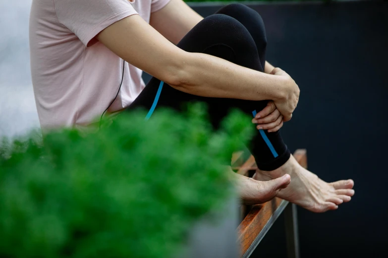 a woman sitting on top of a wooden bench, swollen veins, next to a plant, on rooftop, avatar image