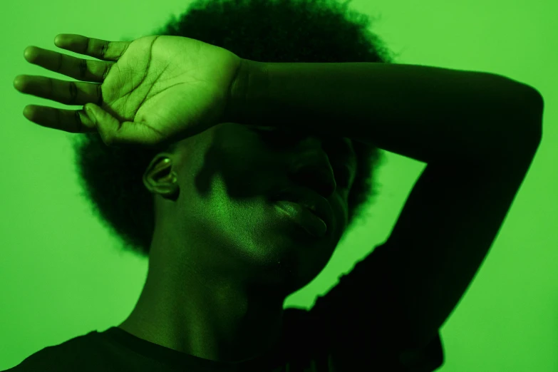 a woman standing in front of a green screen, trending on pexels, afrofuturism, holding his hands up to his face, gradient from green to black, afropunk, soft light from the side