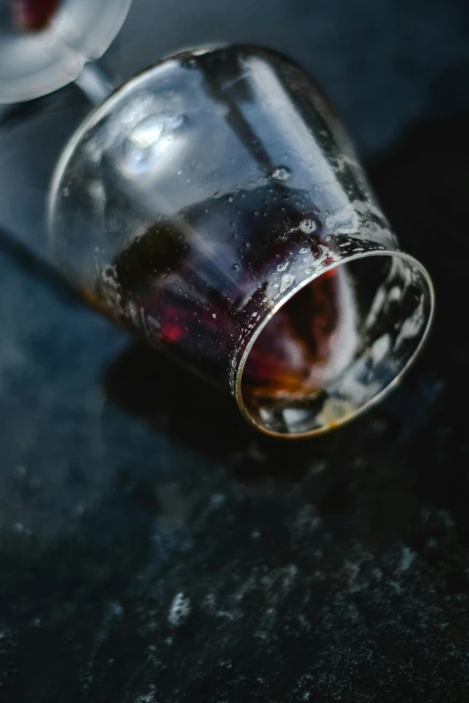 a close up of a wine glass on a table, unsplash, photorealism, ice coffee, medium format, ignant, battered