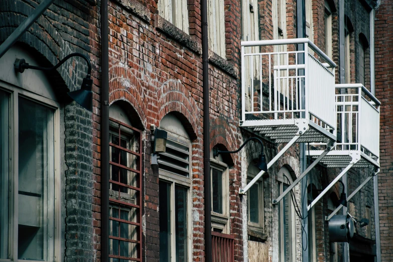 a red fire hydrant sitting on the side of a brick building, by Carey Morris, pexels contest winner, renaissance, crenellated balconies, warehouses, 1990's photo, footbridges between houses