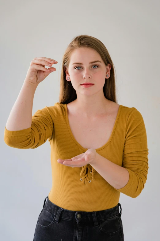 a woman in a yellow shirt posing for a picture, trending on pexels, renaissance, offering the viewer a pill, perfect dynamic posture, casting spells, smooth pale skin