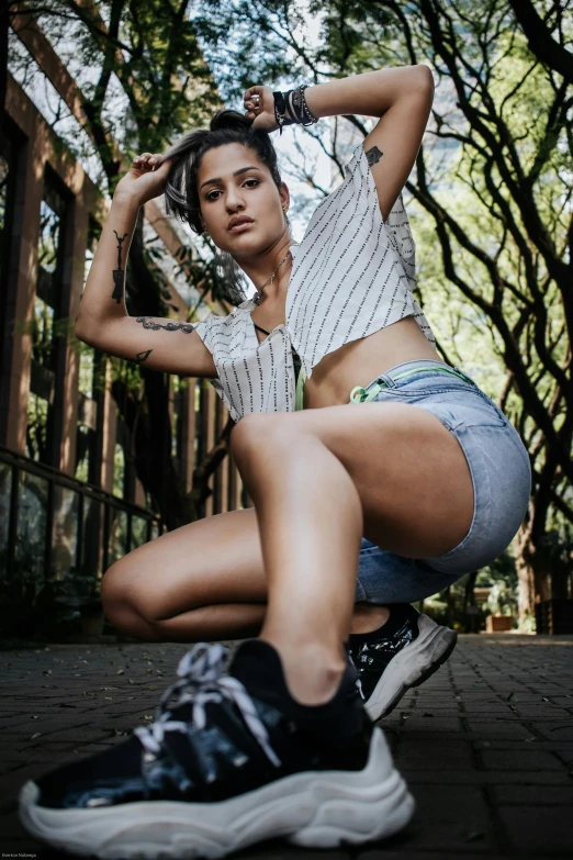 a woman sitting on the ground posing for a picture, croptop and shorts, portrait featured on unsplash, in sao paulo, attractive girl tomboy