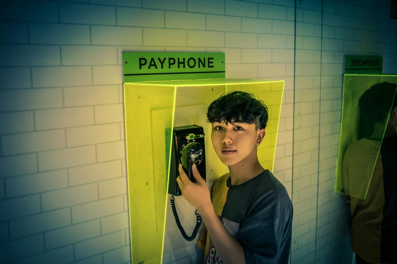 a young man standing in front of a payphone, inspired by Liam Wong, pexels contest winner, made out of plastic, philippe starck, hyung tae kim, ( ( theatrical ) )