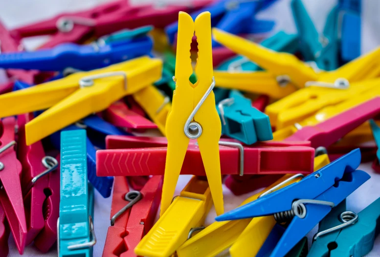 a pile of colorful clothes pegs sitting on top of a table, pexels, solid coloured shapes, yellow, school class, zoomed in