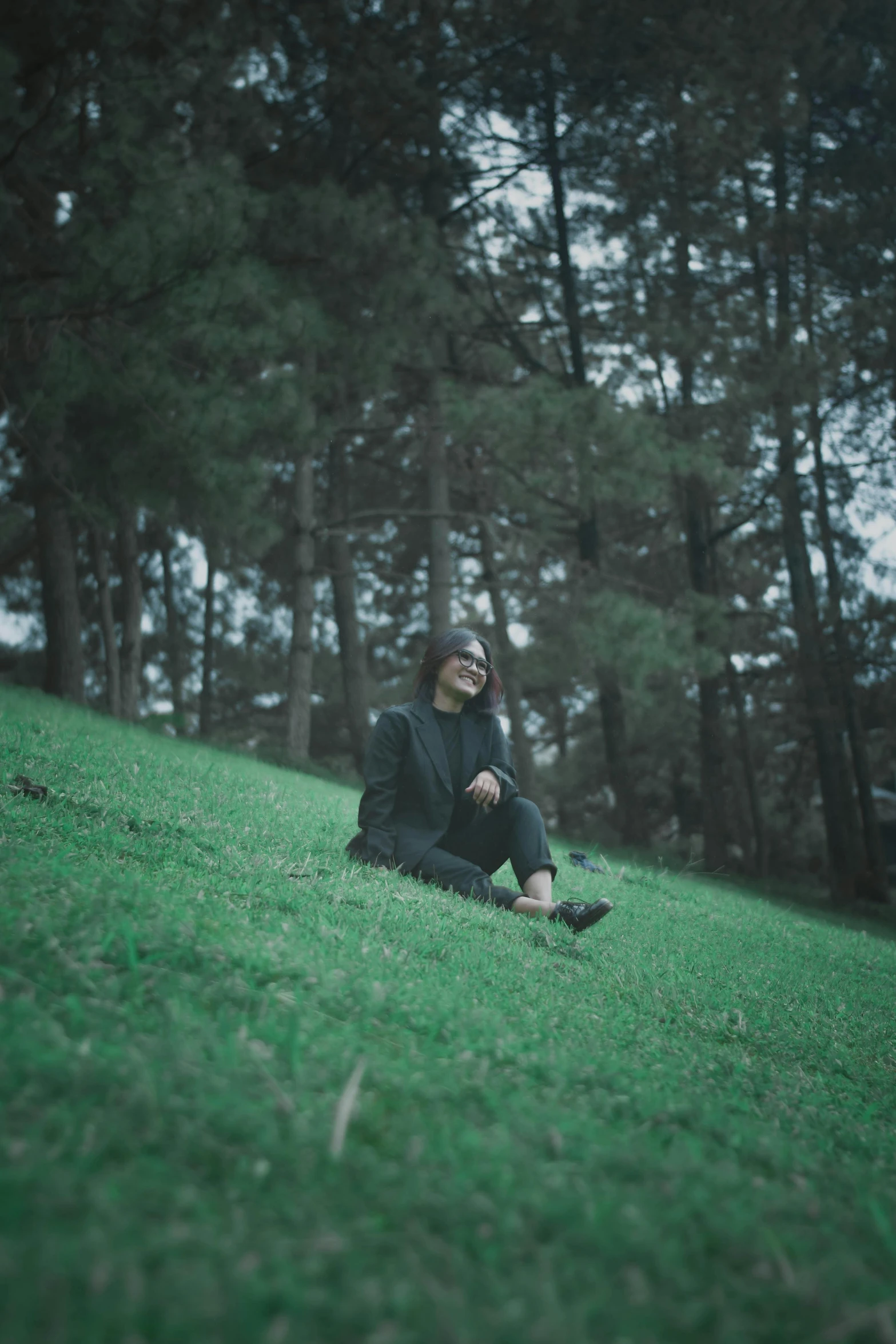 a man sitting on top of a lush green hillside, inspired by Elsa Bleda, sumatraism, low quality photo, ((portrait)), at a park, with black