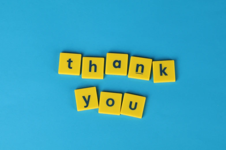 wooden blocks spelling thank you on a blue background, a picture, by Emma Andijewska, pexels, on a yellow canva, square, viewed from below, background image