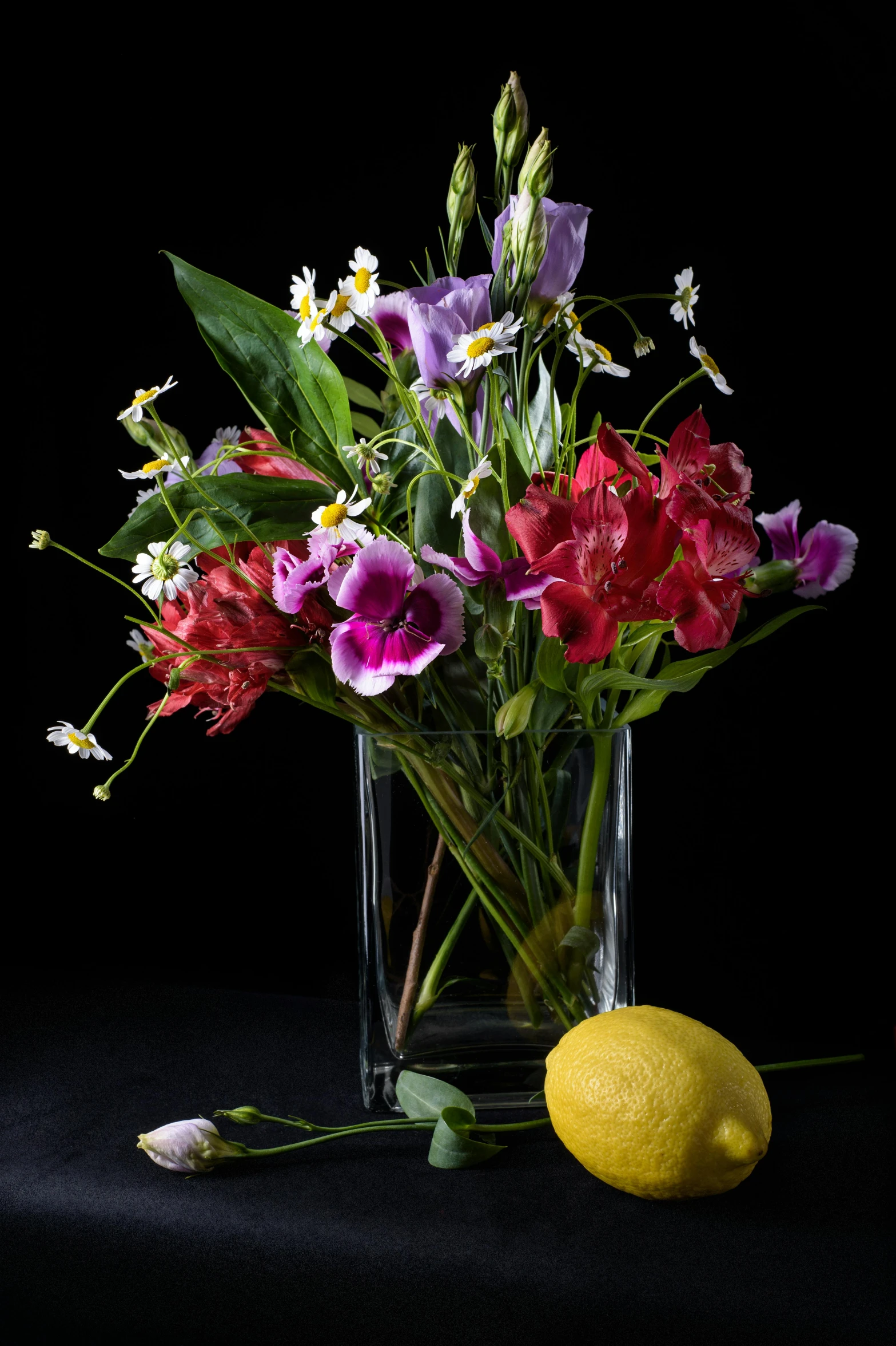 a vase filled with flowers next to a lemon, inspired by François Boquet, shutterstock contest winner, with a black background, full color photograph, edible flowers, purple and red flowers