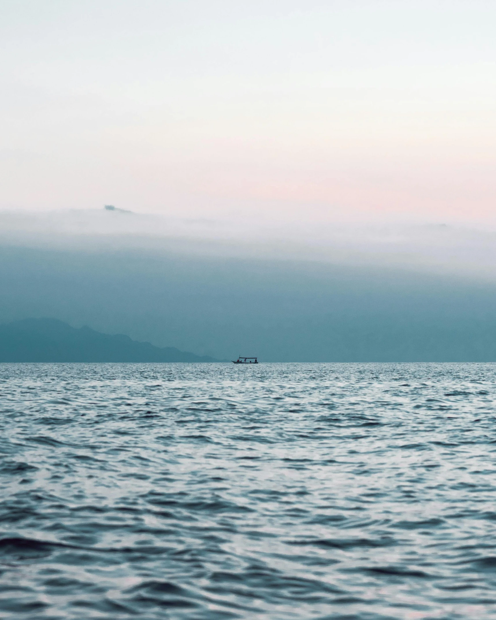 a large body of water with a boat in the distance, trending on unsplash, sumatraism, lgbtq, hazy water, low quality photo, multiple stories