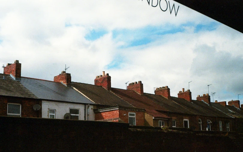 a street sign in front of a row of houses, inspired by Michael Andrews, unsplash, view from window, rossdtaws, 1999 photograph, roofs