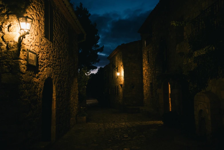 a street lit by a street light at night, pexels contest winner, romanesque, secretly on a village, background image, moody lighting, late afternoon lighting