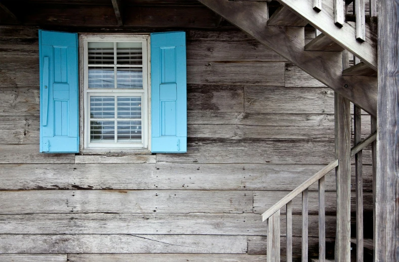 a blue window sitting on the side of a wooden building, inspired by Alfred Wallis, unsplash, wooden stairs, southern gothic, brown and cyan color scheme, white plank siding