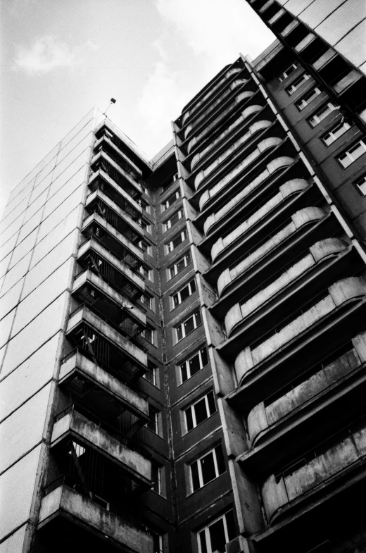 a black and white photo of a tall building, inspired by Thomas Struth, brutalism, dilapidated houses, low angle!!!!, ilford delta 3200, old buildings