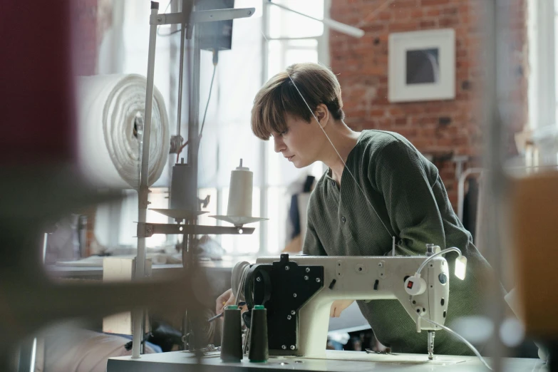 a woman working on a sewing machine in a factory, a portrait, trending on unsplash, ilustration, ignant, very handsome, eva elfie