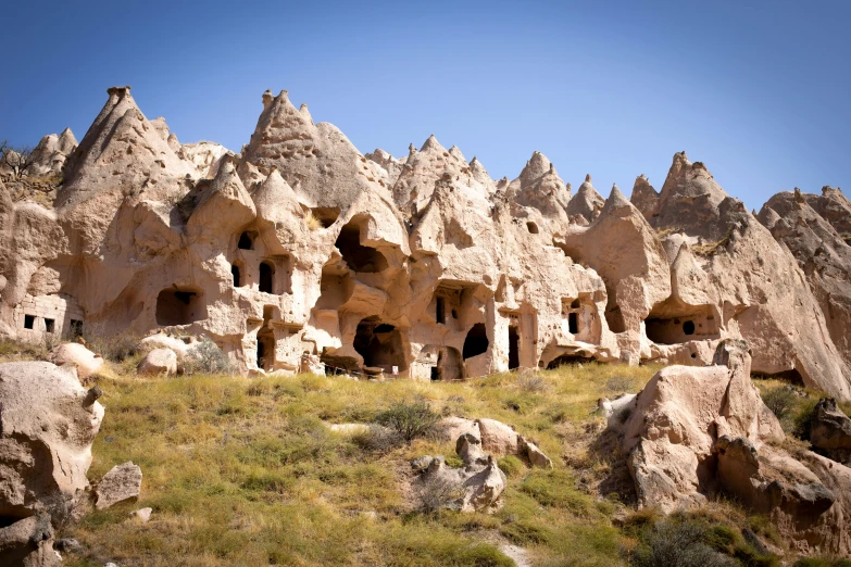 a group of cave houses built into the side of a mountain, pexels contest winner, art nouveau, black domes and spires, victorian arcs of sand, 2000s photo, parks and monuments