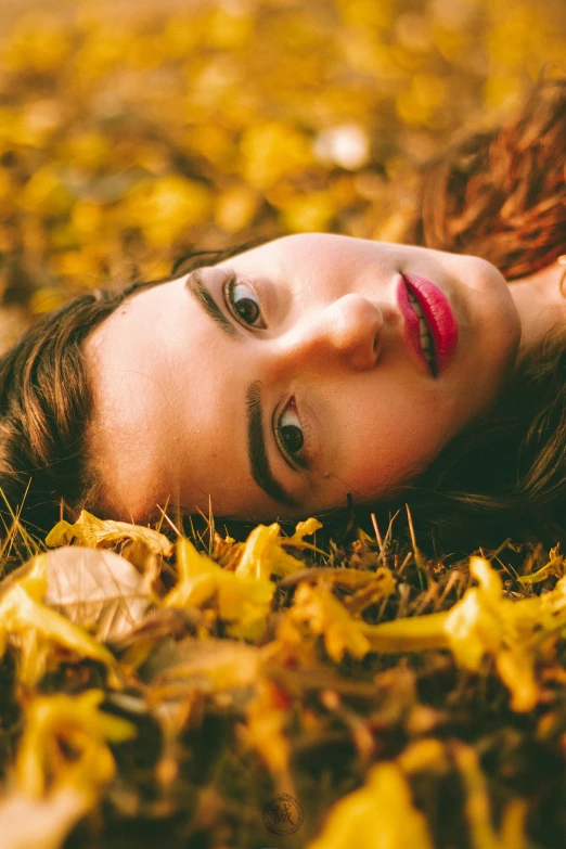 a woman laying on the ground covered in leaves, a picture, profile image, trending photo, yellow makeup, outdoor photo