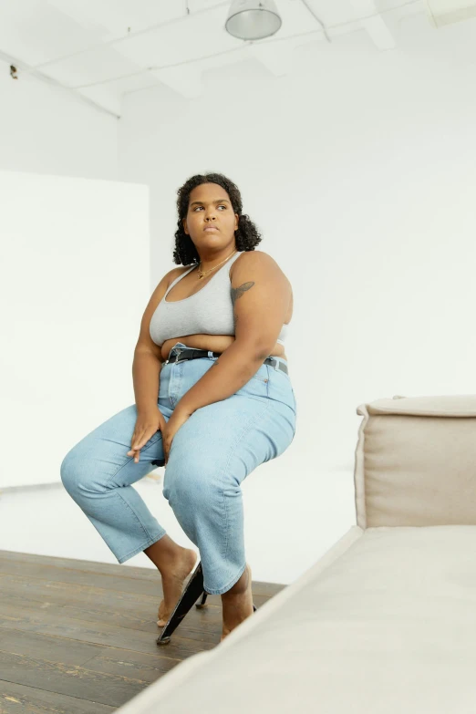 a woman sitting on a couch in a white room, trending on pexels, realism, obese, wearing jeans, looking confident, rectangle