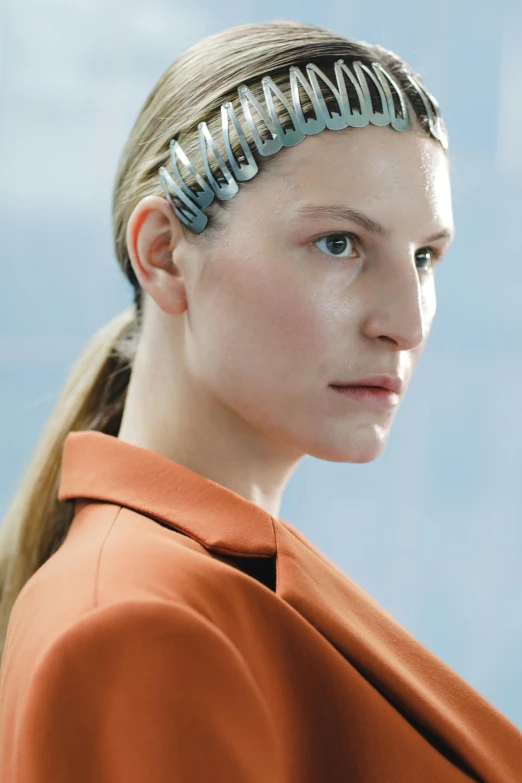 a woman wearing an orange coat and a silver headband, inspired by Otto Stark, brain interface, close up of a blonde woman, machina, promo image