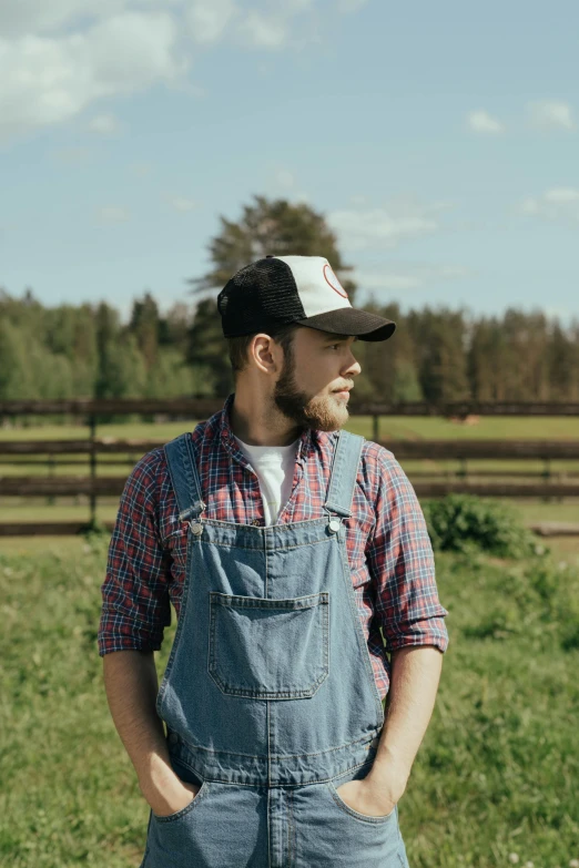 a man in overalls standing in a field, an album cover, by Hallsteinn Sigurðsson, pexels contest winner, wearing a baseball cap, profile image, barn, promotional image