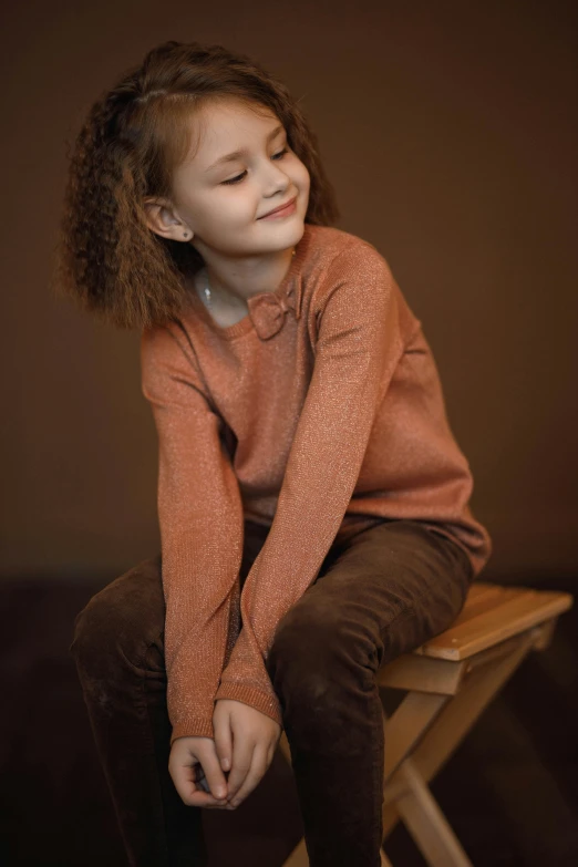a little girl sitting on top of a wooden chair, a portrait, trending on pexels, brown sweater, teenager girl, paul barson, orange color
