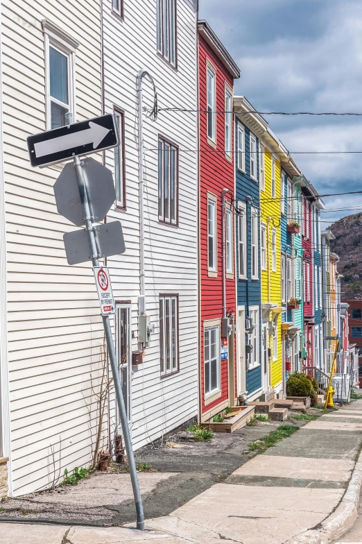 a street sign sitting on the side of a road, by David Donaldson, pexels contest winner, plein air, colorful houses, port, gauthier leblanc, top of the hill