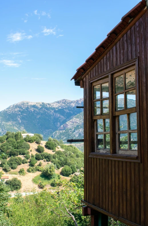 a wooden cabin sitting on top of a lush green hillside, unsplash, modernism, greece, near a window window, square, panoramic